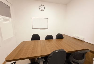 Small meeting room with a wooden table, black chairs, and a whiteboard.
