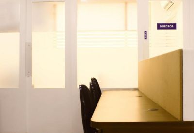 Close-up of a desk partition and chairs near a frosted glass office door.