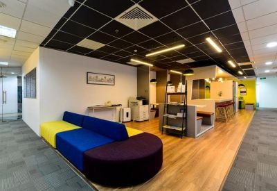 Breakout area with a colorful modular sofa and warm wooden flooring.