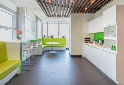 Modern breakroom with lime green seating and a white kitchenette.