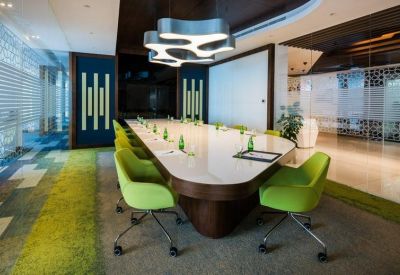 Conference room with a large white table, lime green chairs, and blue wall panels.