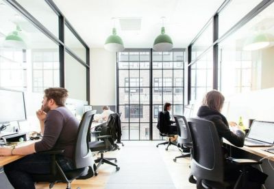 Bright open-plan office with glass partitions and rows of desks.