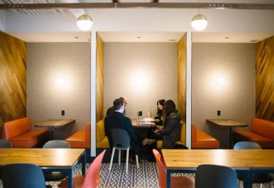 Modern meeting booths with orange seating and wooden accent walls.