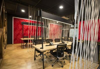 Coworking lounge with communal wooden tables and decorative rope partitions.