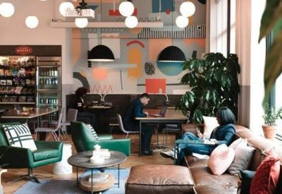 Vibrant lounge area with green armchairs, leather sofas, and colorful wall murals.