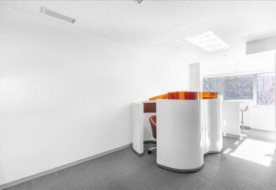 Sleek coworking area with curved white privacy pods and orange glass accents.