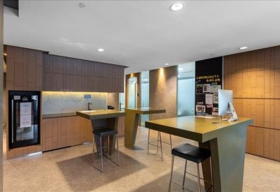 Modern communal break area with high tables, stools, and a small kitchenette.