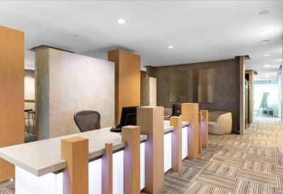 Bright reception area featuring a white desk with wooden accents and patterned carpet.