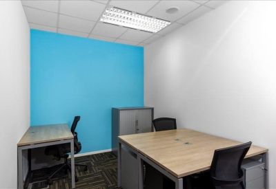 Small private office with a bright blue feature wall and wooden desks.