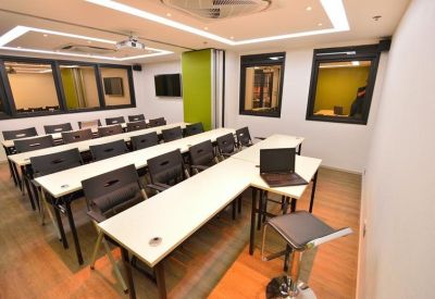Classroom-style training room with rows of white desks and black chairs.