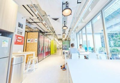 Bright communal dining area with long tables, designer lighting, and floor-to-ceiling windows.