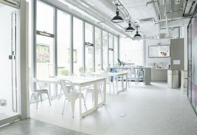 Modern open-plan workspace featuring white desks and a wall of windows letting in natural light.