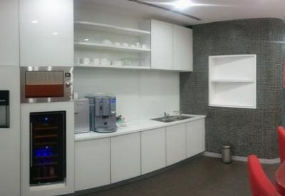 Modern communal kitchen area with white cabinetry and a long red breakfast bar.