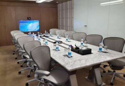 Long marble meeting table with grey ergonomic chairs and video conferencing screen.