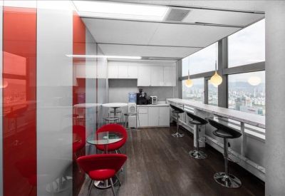 Small kitchen area with red chairs and a bar counter with city view.