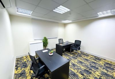 Private office featuring two black desks and patterned yellow carpet.
