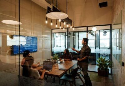 Modern glass-walled meeting room with a wooden table and professional presentation screen.