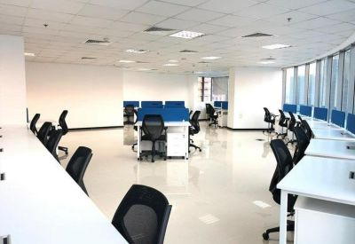 Open-plan office space with white workstations and bright, reflective flooring.