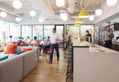 Bright breakout kitchen area with white counters and a series of spherical pendant lights.