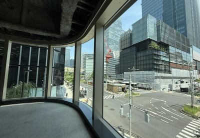 An empty office floor with large curved windows overlooking a busy city intersection.