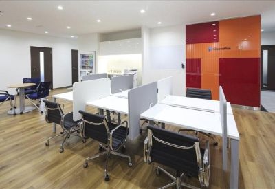 Vibrant coworking area with white desks and a bold orange and red accent wall.