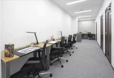 Long row of dedicated desks with black mesh chairs and personal lamps.