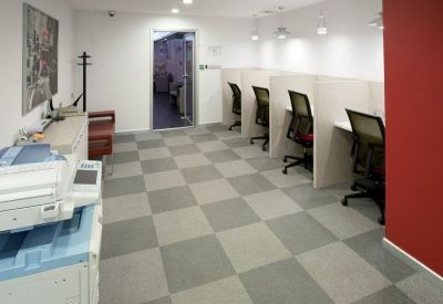 Open-plan coworking area with individual workstations and a bold red feature wall.