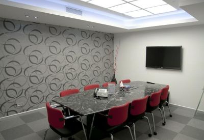 Modern meeting room with a dark marble table, red chairs, and a geometric patterned feature wall.