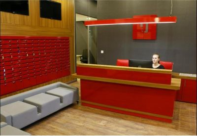 Modern reception area with a vibrant red front desk and grey bench seating.