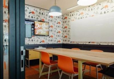 Creative meeting room with patterned wallpaper, orange chairs, and a large whiteboard.