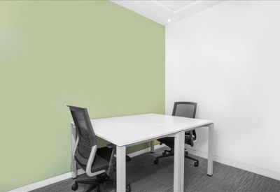 Private two-person office suite with a pale green feature wall and white desks.