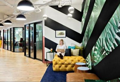 Modern workspace with chevron-patterned walls and a bright yellow tufted ottoman.