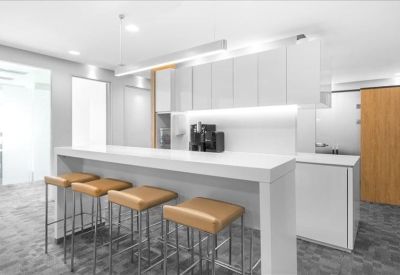 Communal kitchen area with a high white breakfast bar and tan leather stools.