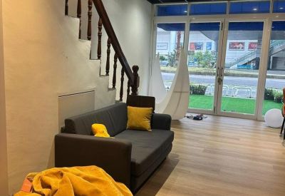 Cozy communal lounge area featuring a grey sofa with yellow pillows and a bright yellow bean bag chair.