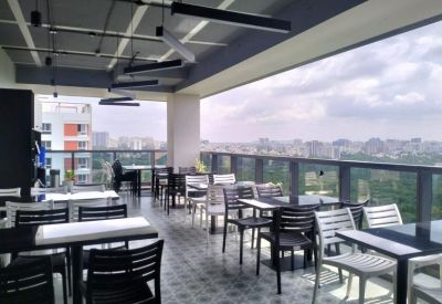 Covered rooftop café and communal area with tables, chairs, and panoramic city views.