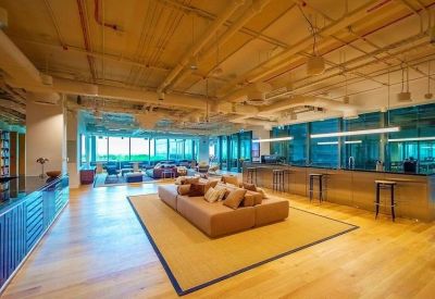 Spacious communal lounge with wooden floors, industrial ceiling, and plush tan sofa.
