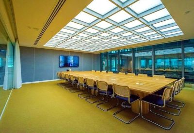 Large boardroom with a long wooden table under a square grid skylight and yellow carpeting.