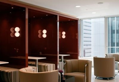 Communal breakout area with warm wood-paneled booths and stylish armchair seating.