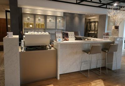 Marble-topped reception and cafe counter with modern bar seating and a sleek espresso machine.