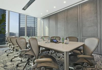 Professional boardroom with grey ergonomic chairs around a large table and views of city skyscrapers.
