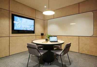 Small meeting room with round table, grey chairs, and a whiteboard.