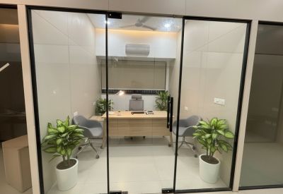 Private office suite viewed through glass doors with a wooden desk and grey armchairs.