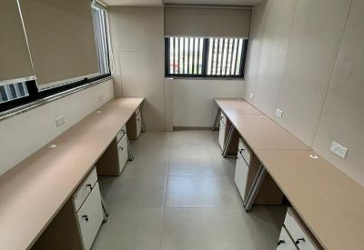 Empty modern workstation area with long beige desks and white under-desk storage cabinets.
