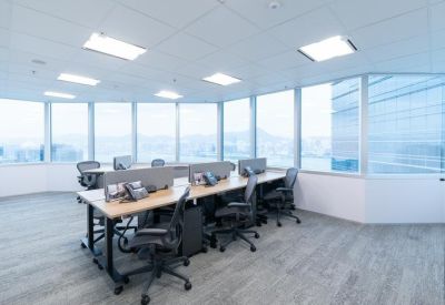 Bright open-plan office area with rows of workstations and wraparound windows.