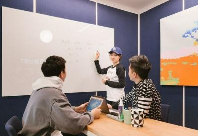 Team meeting in a room with blue walls, a large whiteboard, and colorful artwork.