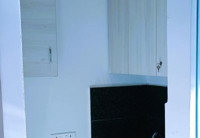 Small kitchenette area with black countertops and light wood upper cabinets.