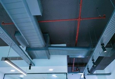 Industrial style ceiling with exposed ductwork, red fire pipes, and track lighting.