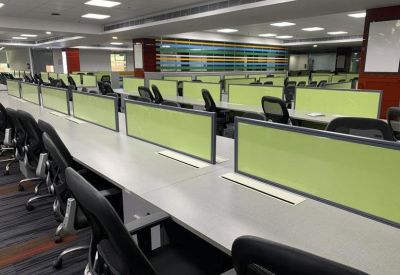 Large open-plan workspace featuring long rows of white desks with lime green privacy dividers.