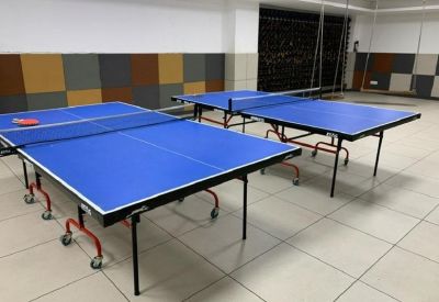 Recreational room featuring two blue professional table tennis tables on a tiled floor.