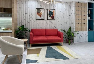 Communal lounge area with a red sofa, patterned rug, and potted plants.